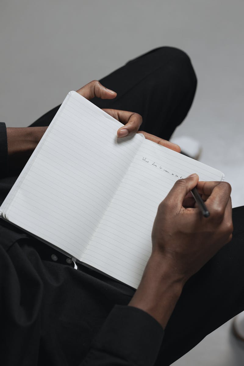 Close-up of a person jotting down notes in a notebook, focusing on hands and pen.